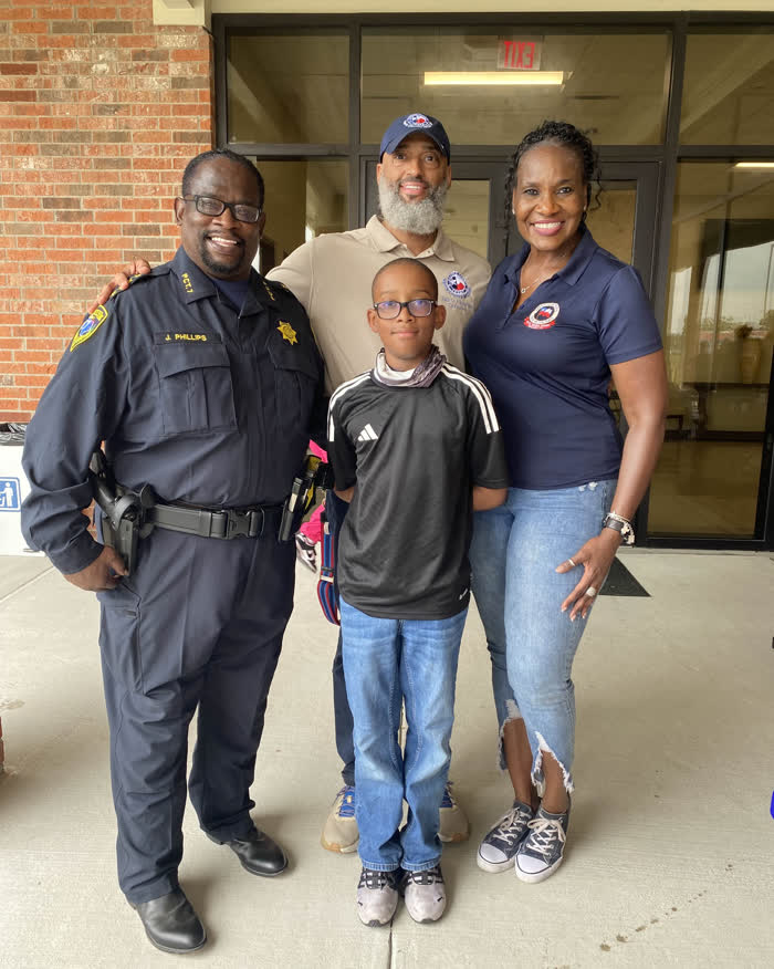 Tahir Charles with a Harris County constable, a young resident and another adult outside a district building.