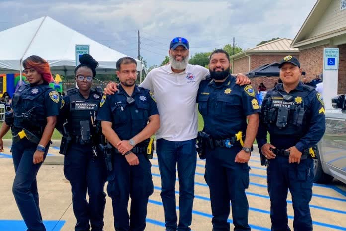 Tahir Charles standing with five Harris County constable deputies at an outdoor district event.