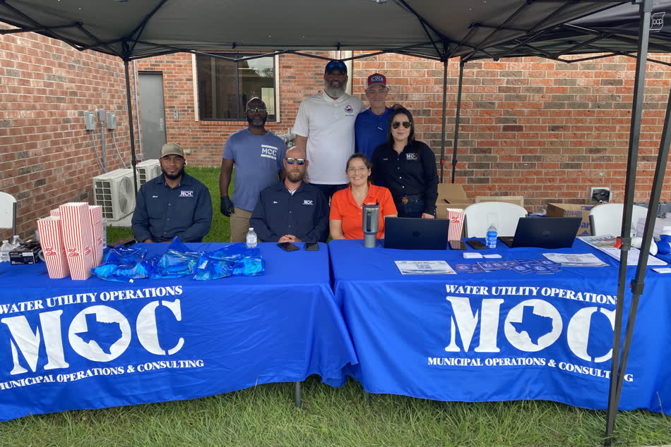 Staff of Municipal Operations and Consulting behind two blue tables under a canopy at a district event.